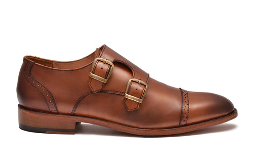 Brown leather shoe with gold buckles on a white background
