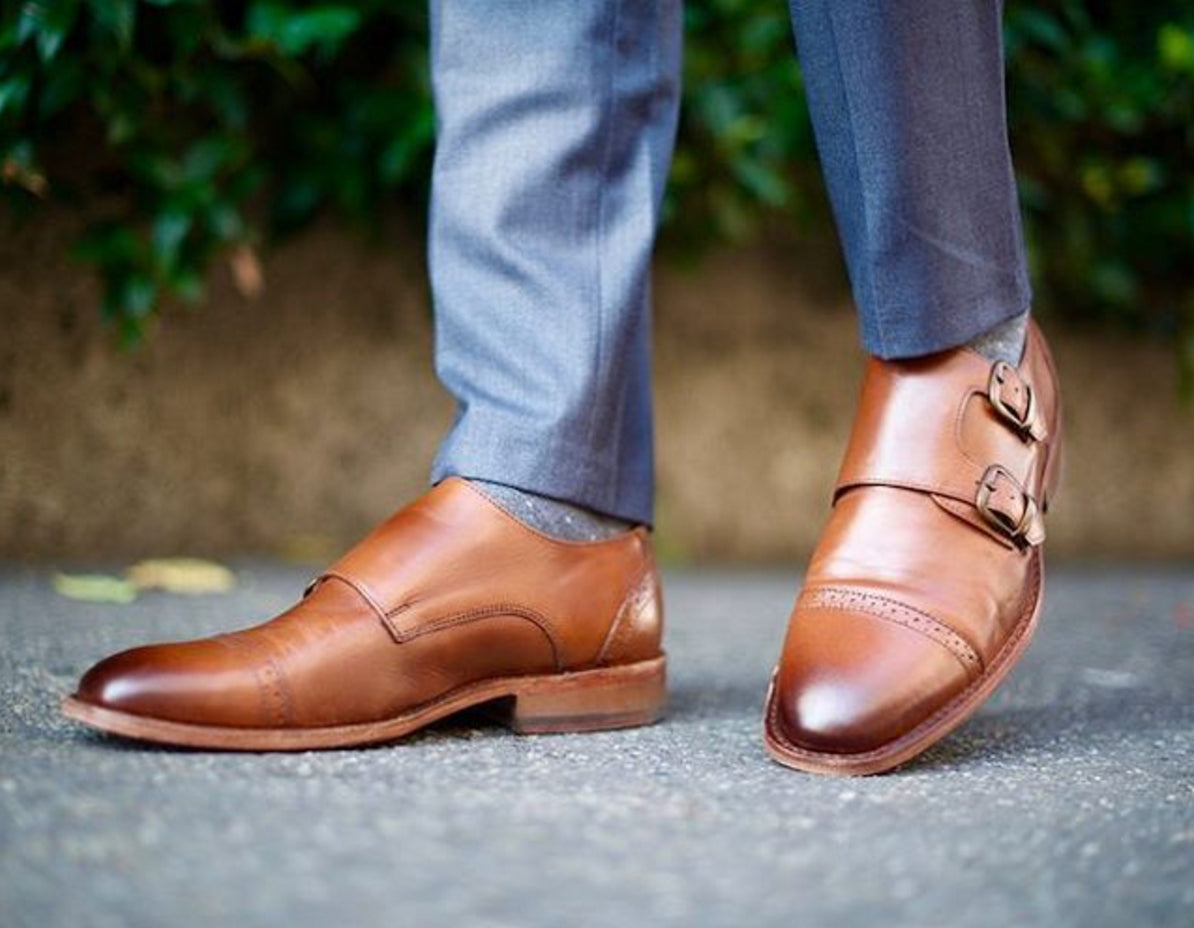 Brown leather shoes with buckles worn by a person on a blurred outdoor background  by KOCH & CO.